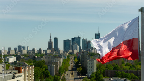 Warsaw skyline from drone with a large Polish flag waving above the city on a clear day