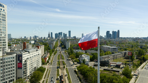 Warsaw skyline from drone with a large Polish flag waving above the city on a clear day
