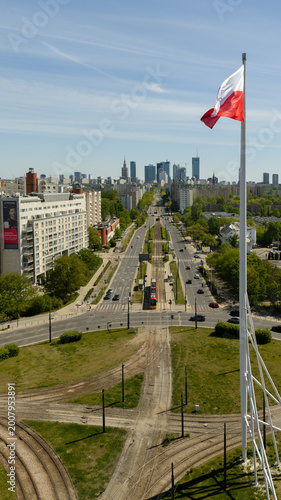 Warsaw skyline from drone with a large Polish flag waving above the city on a clear day