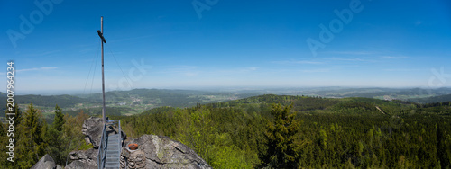Panoramic view from the Nebelstein summit with wooden cross, rocky peak, and vast forest landscape in Lower Austria