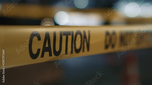 Yellow caution do not enter tape at night with red and blue flashing lights close up demonstrates restricted access site security and incident atmosphere with focus on warning message