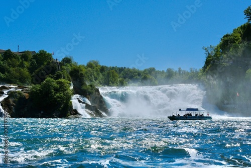 Foto Tour boat approaching Rhine Falls in Switzerland with dramatic cascading water a
