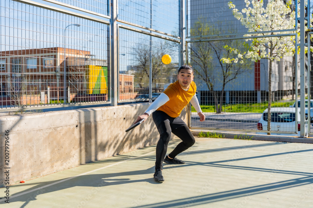 Obraz premium Young man playing pickleball on outdoor court