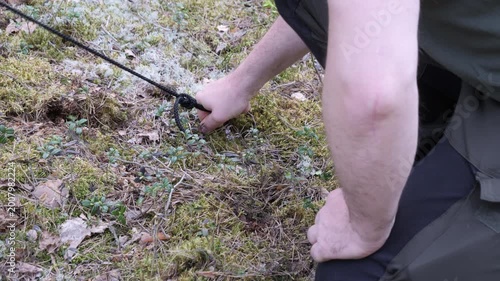 Setting Up Tent in Forest Using Rock to Secure Stake