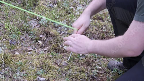 Close Up Securing Tent Guy Line with Stake in Forest