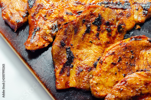 Grilled pork chops sizzle on a dark cutting board
