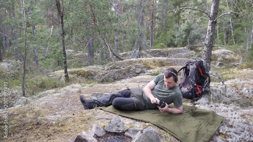 Hiker Resting on Tarp and Using Phone in Forest