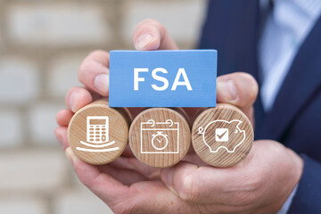 Concept of FSA Flexible Spending Account. Business person holding blocks with icons sees the abbreviation FSA.