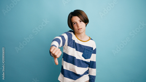 Foto Boy expressing negative sentiment, showing dislike or rejection with a thumbs do