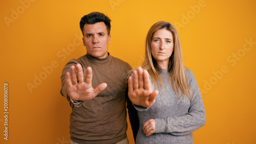 Man and woman making a protective stop gesture, expressing denial and setting boundaries in a serious manner