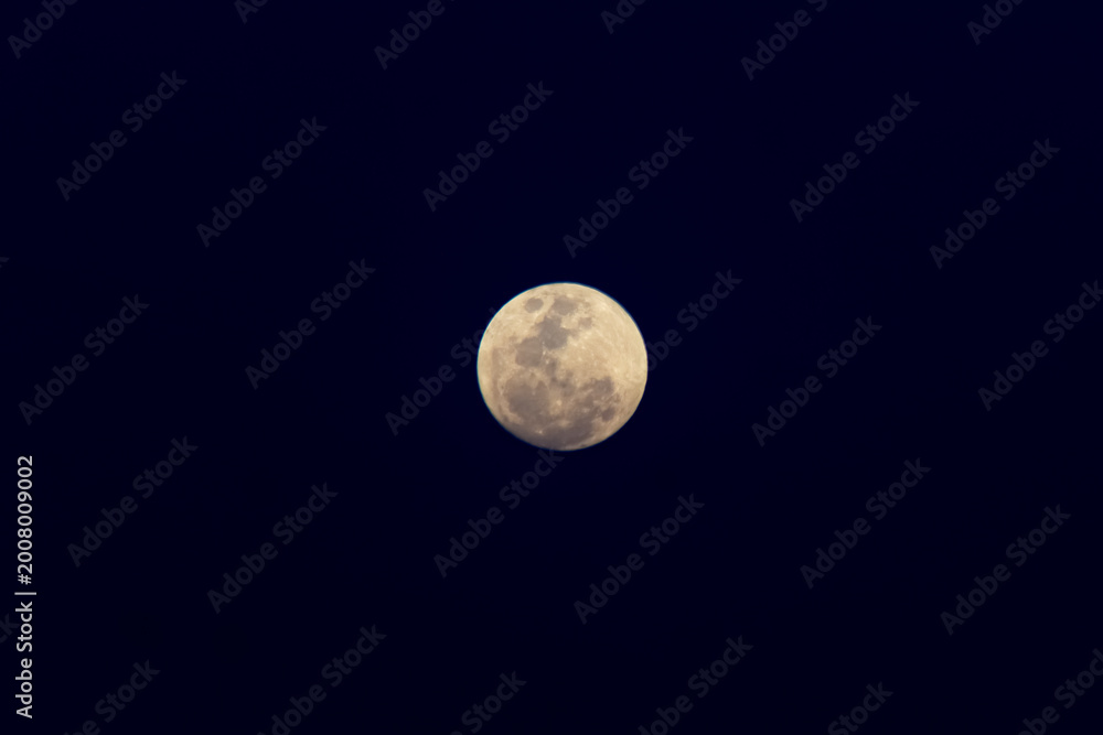 Obraz premium Full moon in the night sky with clouds and sunbeams.