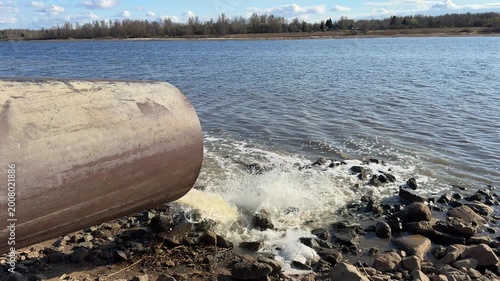 Wastewater discharge from pipe into river water, environmental pollution and contamination, dirty sewage flowing into nature