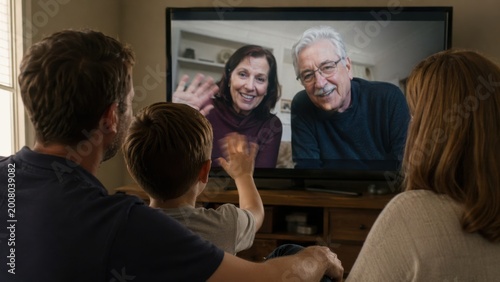 multi generational family watching tv together in cozy living room with warm lighting