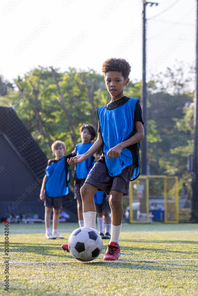 Fototapeta premium Group of boys and girls enjoy to practice to play soccer together in football field with day light and they look happy to exercise to get good health.