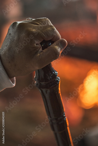 Hand holding traditional staff near fire during Samaritan Passover ritual