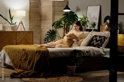 Young woman reading book on...