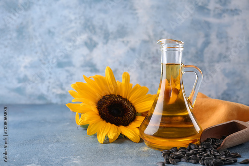 Foto Decanter of sunflower oil, napkin and scoop of seeds on blue grunge background,