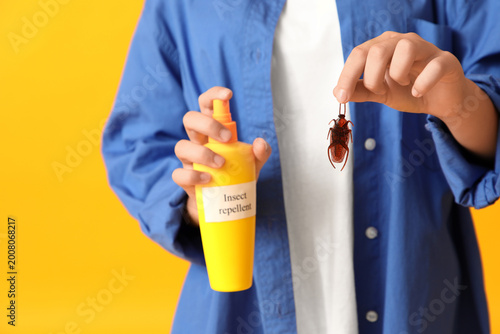 Foto Teenage girl with cockroach and bottle of insect repellent on yellow background,