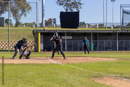 Pitch arriving, batter swinging bat scoring run, catcher catching, umpire signaling strike