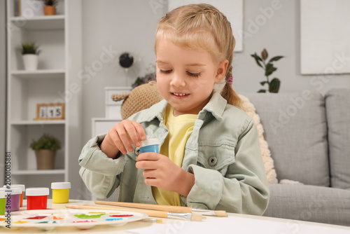 Cute little girl with paints at home