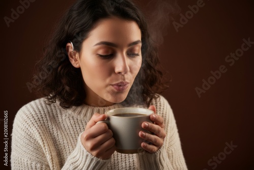 Portrait of young woman blowing on hot steaming cup of coffee or tea diversity people concept