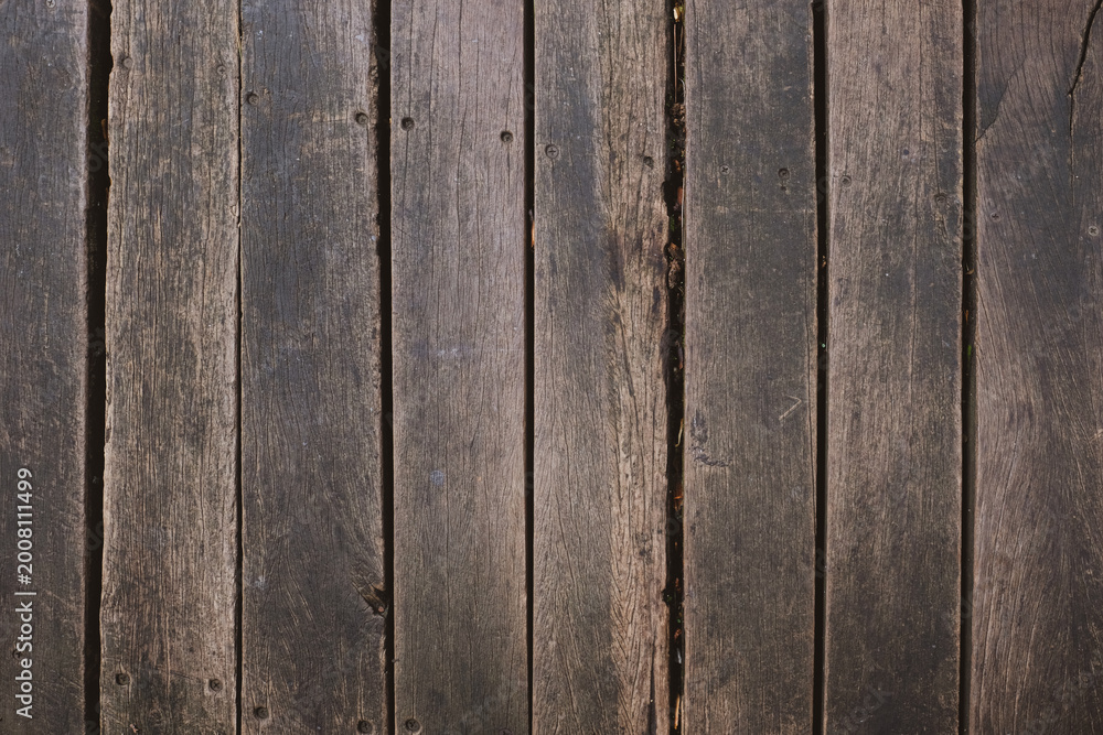 Fototapeta premium Weathered wooden boards aligned vertically with visible grain and seams. Suitable for rustic backgrounds and wood texture overlays.