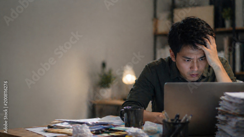 Stressed man working late on laptop feeling frustrated