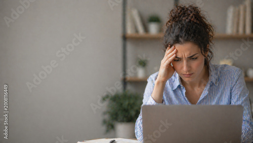 Stressed woman feeling frustrated working on laptop