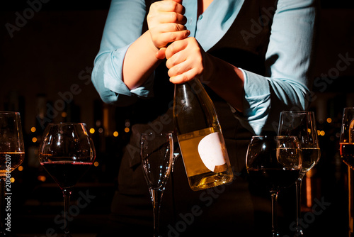 Close up of woman hands removing cork from bottle of white wine. Professional preparation for degustation and service.