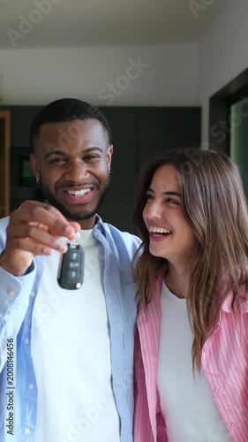 An excited young couple joyfully shows off the keys to their new car, celebrating their recent purchase and future adventures together.