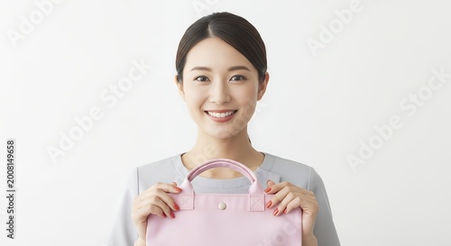 Smiling woman holding pink handbag against white backdrop