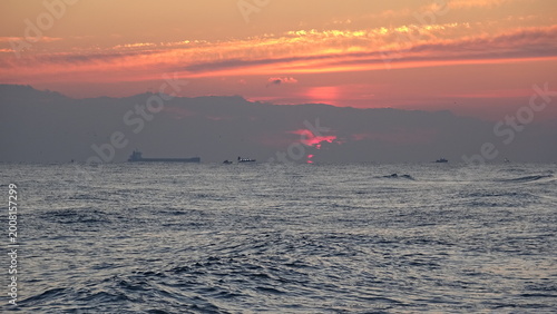 Red Dawn Sunrise over East Sea Horizon with Cargo Ships.
A dramatic red dawn sky over the calm East Sea in Gangneung, South Korea, featuring cargo ships on the horizon during sunrise.