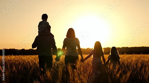 Happy Family Walking Together in a Golden Wheat Field at Sunset.