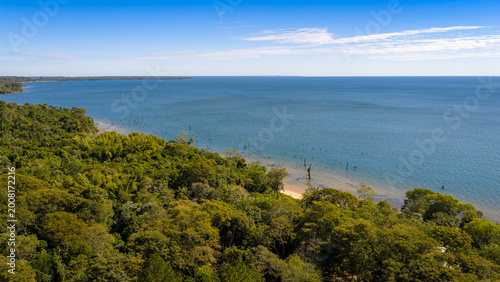 Aerial view of remote shoreline and forest along Parana River reservoir, ideal for travel and nature content.