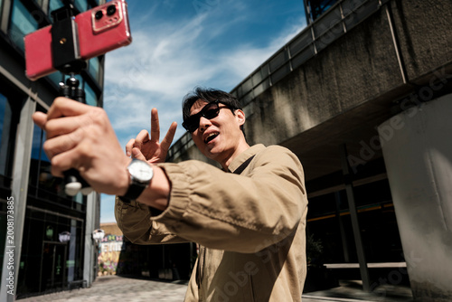 Asian man vlogging urban lifestyle showing peace sign
