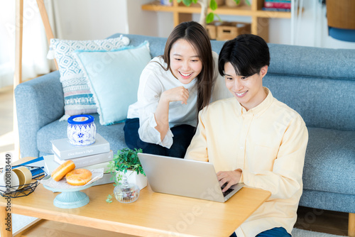 リビングでスマホを見る若いカップル