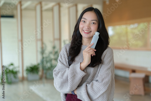 Asian woman holding personal alcohol spray bottle
