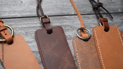 Four handcrafted leather tags in various brown shades on a rustic wooden background