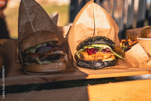 Obraz na płótnie Gourmet burgers served in brown paper bags on wooden tray