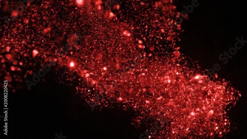 Abstract red glowing particles moving across a dark black background, creating a dynamic and visually appealing effect
