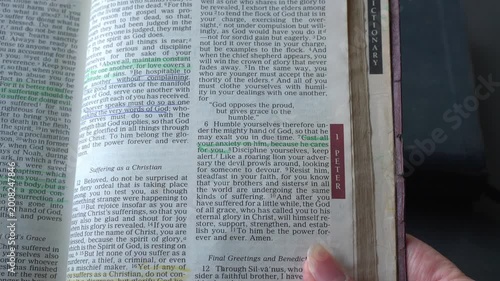 Holy Bible open up to the book of 1 Peter of the new testament, zooming into Chapter 5 verse 7 on casting anxiety onto the Lord. New Revised Standard Version.