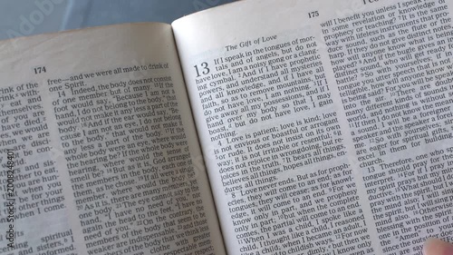 Holy Bible open up to the book of 1 Corinthians of the new testament, zooming into Chapter 13 verses 4 to 8 on love. New Revised Standard Version.