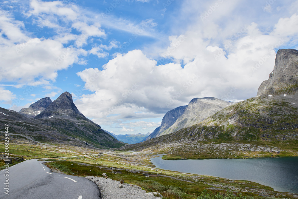 Fototapeta premium Blue sky, mountain and clouds with road of landscape, valley or beautiful climate in nature. Empty, space and wilderness of river stream or street with greenery, snow or lake for outdoor destination