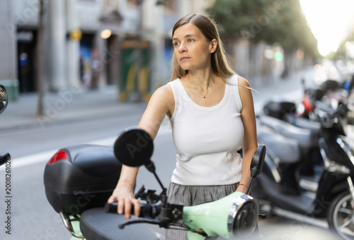 Tableau sur toile At parking lot, woman starts moped and starts ride around European capital city