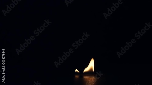 Single realistic fire flame burning, flickering, and gradually dying out isolated on a pure black background for VFX overlay and compositing.