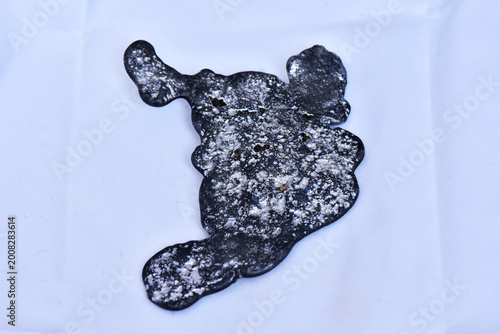 A top-down studio shot of a solid piece of recycled lead metal ingot obtained from smelting old waste batteries, isolated on a white background.