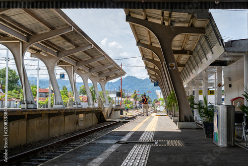 Railway station platform with worker standing near tracks under modern canopy structure with strong perspective and leading lines