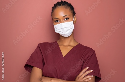 Young nurse wearing mask with crossed arms in studio