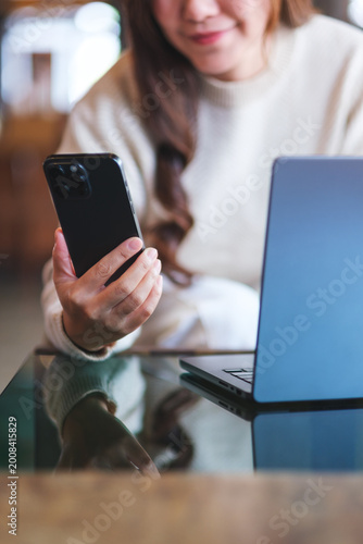 Vertical closeup image of a woman using smart phone and laptop computer