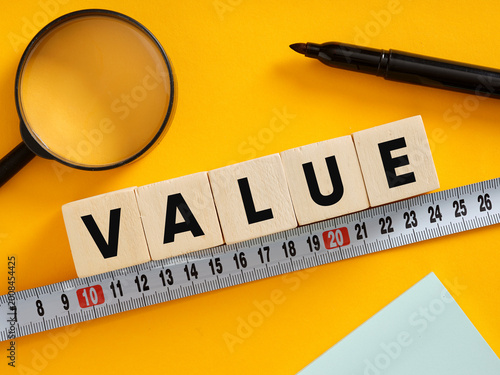 Measuring value with magnifying glass, marker and measuring tape on yellow background